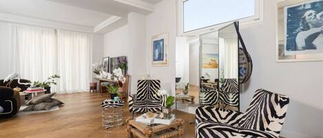 A spacious living room with a large mirror, zebra-striped chairs, and a wooden coffee table.