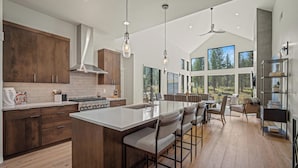 A modern kitchen with a large island, wooden cabinets, and a view of the outdoors. - Forestbrook Luxury with Access to Exclusive Golf (Sunriver)