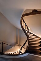 A spiral staircase with wooden steps and a wooden railing, leading to an upper floor.