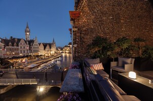 A rooftop terrace with a view of a historic cityscape, including a prominent clock tower.