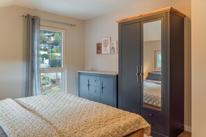 Un dormitorio con cama, armario, ventana y puerta.