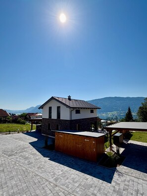 Una casa moderna con un amplio patio, una terraza de madera y vistas a la montaña.