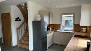A modern kitchen with a built-in refrigerator, wooden staircase, and a window providing a view of the outside. - Holiday Home 'Steinrose' with Lake View, Private Terrace and Wi-Fi (Bodensdorf)