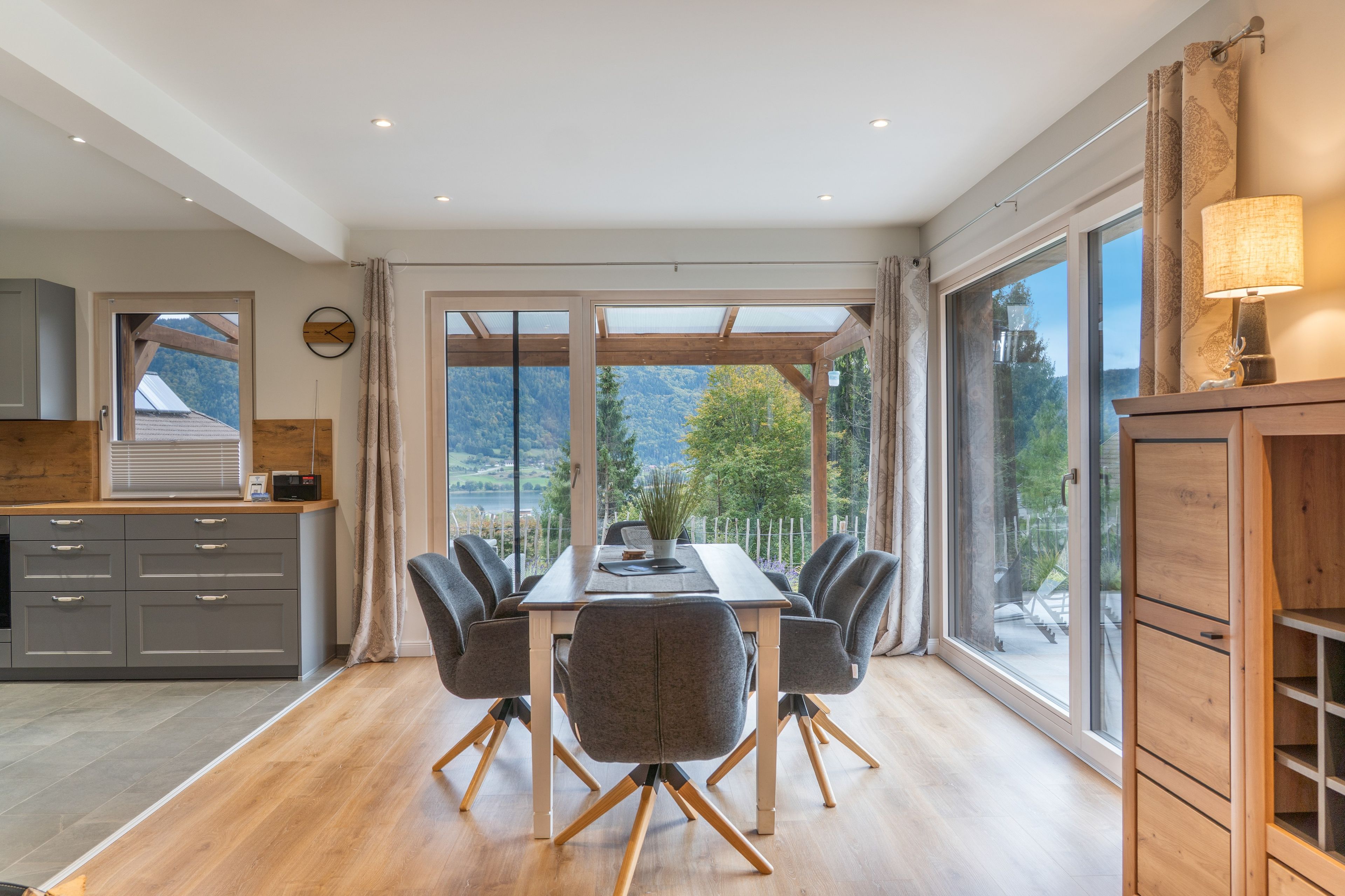 Un espace repas comprenant une table et des chaises, de grandes fenêtres et une vue sur l’extérieur.