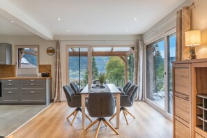Un comedor con mesa y sillas, ventanas amplias y vista al exterior.