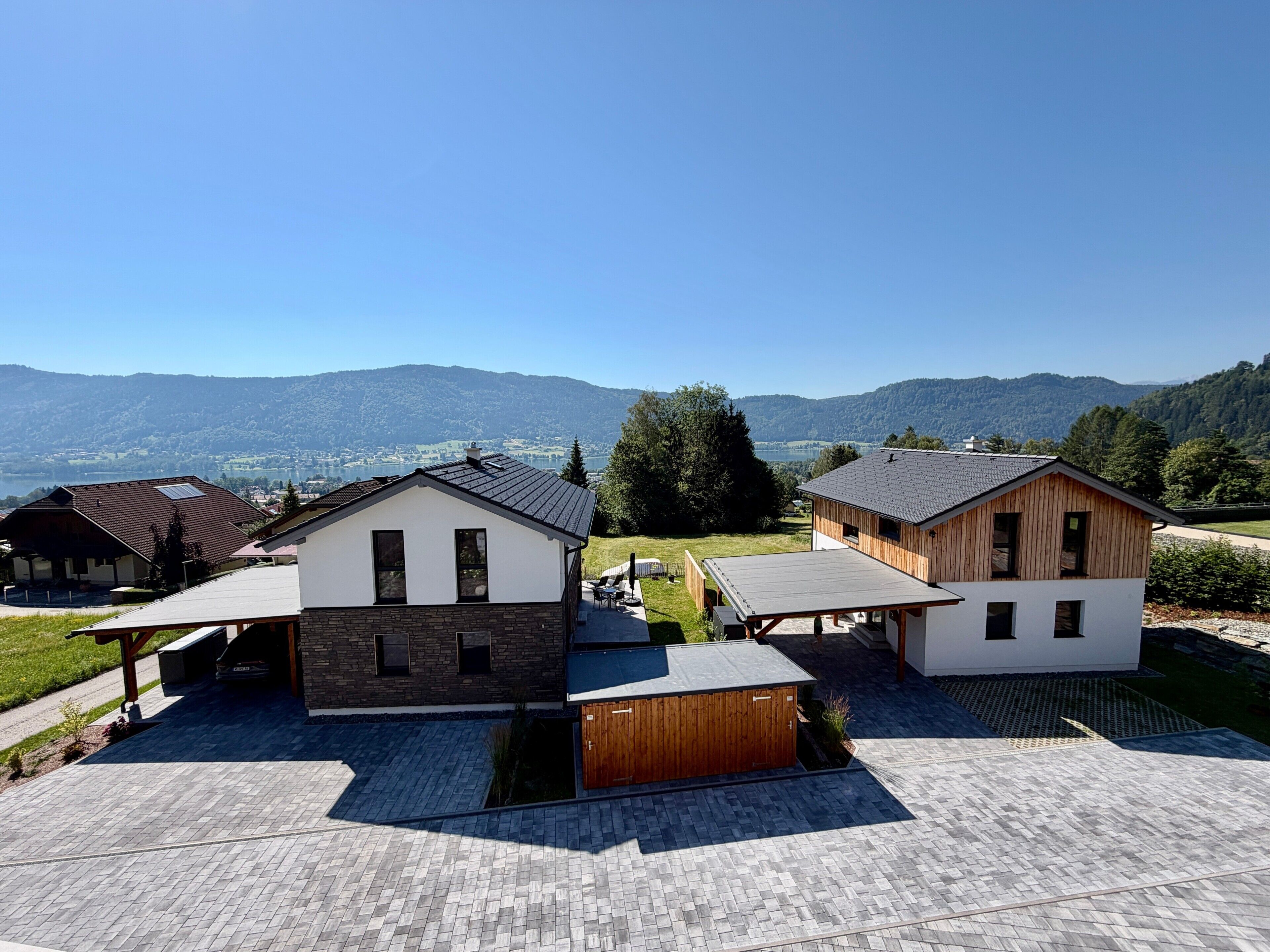 Un quartier résidentiel avec des maisons modernes, un patio couvert et une vue sur les montagnes et un lac.