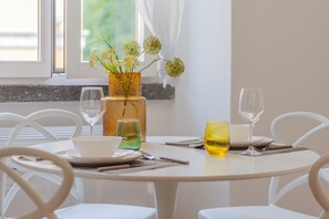 A dining table set with a vase of flowers, two glasses, and a plate.