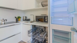 A modern kitchen with white cabinetry, a built-in dishwasher, a microwave, and a water dispenser.