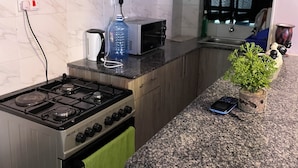 A compact kitchen with a gas stove, a toaster, and a sink. - Chic 1-bedroom apartment in wonderful Nairobi with AC, fitness room (Nairobi)