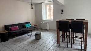 Un salon avec un canapé, une table à manger et des chaises, un radiateur et une fenêtre.