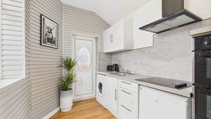 Una cocina moderna con armarios blancos, horno empotrado y campana de acero inoxidable.