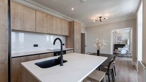 A modern kitchen with a large island, wooden cabinets, and a marble countertop. - Host & Stay | Albion Place (Ramsgate)