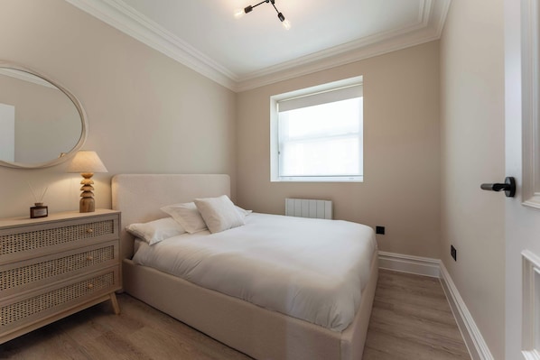 Un dormitorio con cama, cómoda, espejo y ventana.