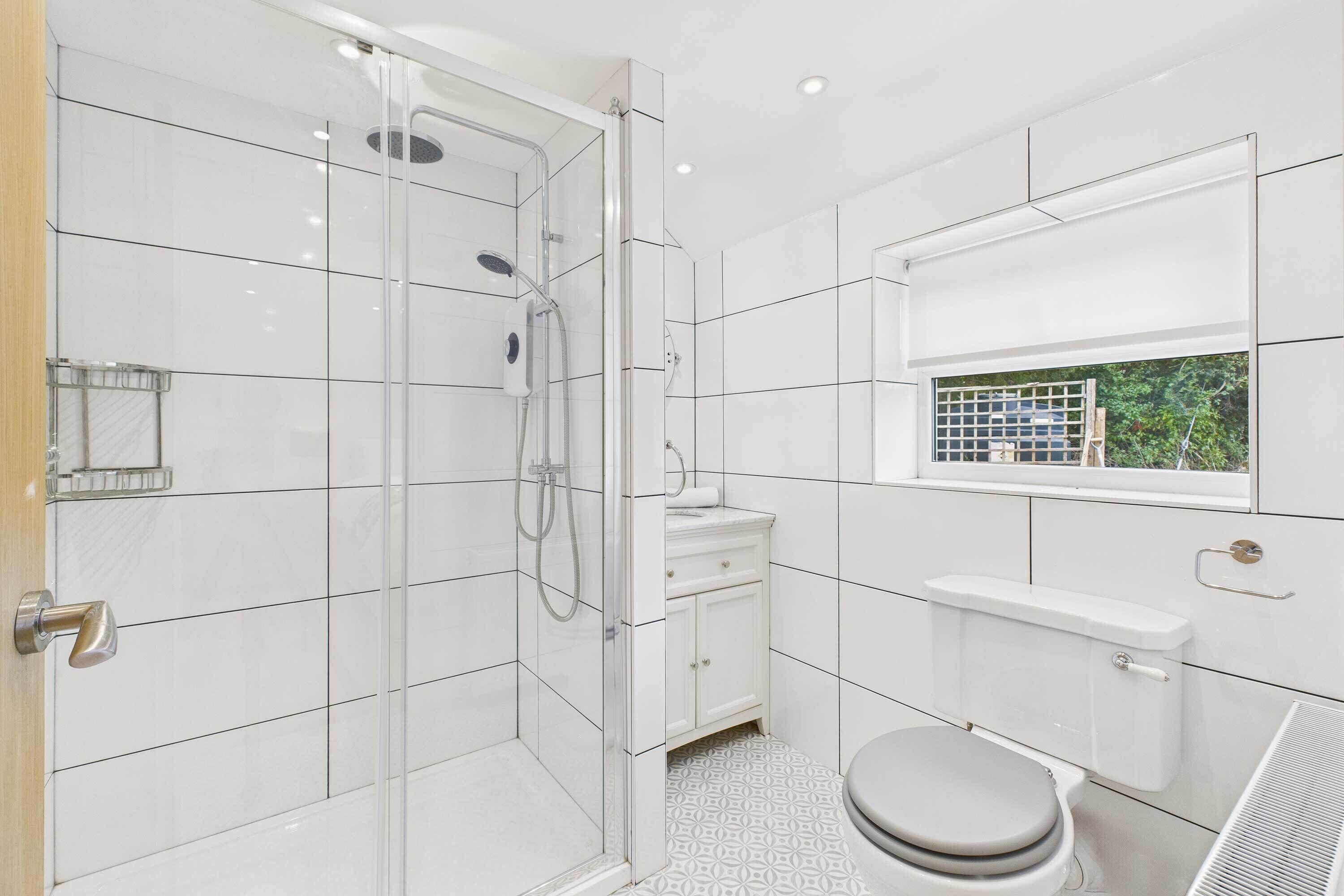 A modern bathroom with a glass-enclosed shower, a toilet, and a sink.