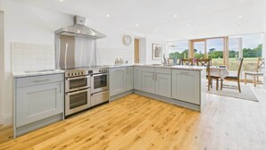 A modern kitchen with grey cabinets, stainless steel appliances, and a wooden floor. - Host & Stay | Merrow Cottage (Great Malvern)