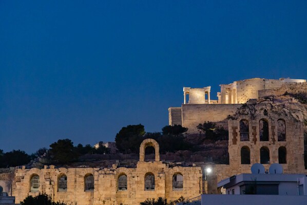 A historic stone building with arched windows and a flat roof, surrounded by modern structures. - Massive 2-combo apt Unbeatable Acropolis Views 9pax (Athens)