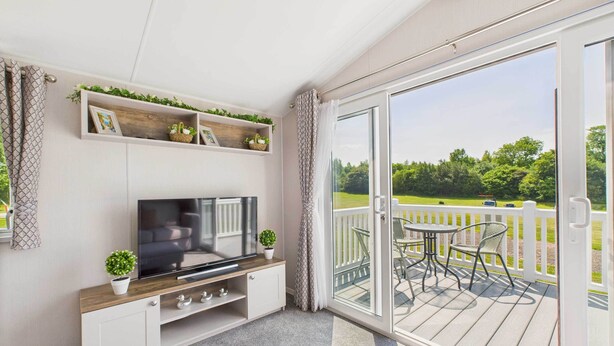 A balcony with a TV, white cabinets, and potted plants. - Host & Stay | Woodpecker Lodge (Swannington)