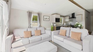 A compact living space with a sofa set, kitchenette, and a dining area. - Host & Stay | Woodpecker Lodge (Swannington)