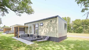A modern mobile home with a patio area, outdoor seating, and a covered deck.