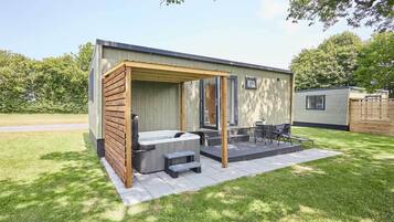Un espace moderne aménagé à l’extérieur avec un bain à remous, une pergola en bois, un coin salon et une petite table.
