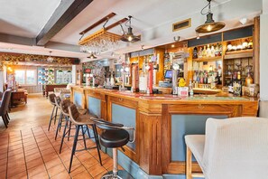 Eine Bar mit Holzbalken, Barhocker und Regalen voller Flaschen.