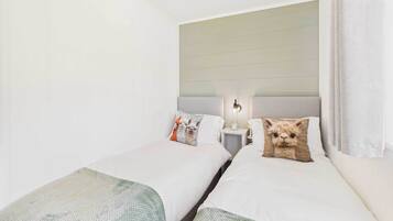 Une chambre d’hôtel avec deux lits simples, chacun étant équipé d’un oreiller et d’une table de chevet avec une lampe.