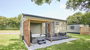 A modern outdoor hot tub area with a wooden pergola, a seating area, and a small table.