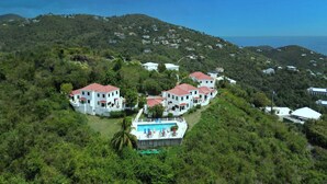 A hillside property with multiple white buildings, a swimming pool, and lush greenery. - Sunset Dream - 1BR Hillside Retreat – A/C & Ocean Views, Newly Updated. (St John)
