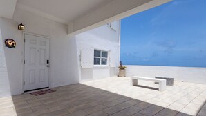 Un espacio exterior amplio con una puerta blanca, un banco y una ventana pequeña.