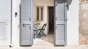 A doorway with open shutters leading to a room with a table and chairs. - Pescamare Apartment Polignano A Mare (Polignano a Mare)