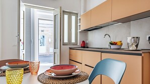 A modern kitchen with a large window, a sink, and a dining area with a table set for two. - Pescamare Apartment Polignano A Mare (Polignano a Mare)