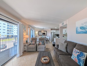 Um apartamento moderno com área de refeições, cozinha e varanda com vista para um edifício.