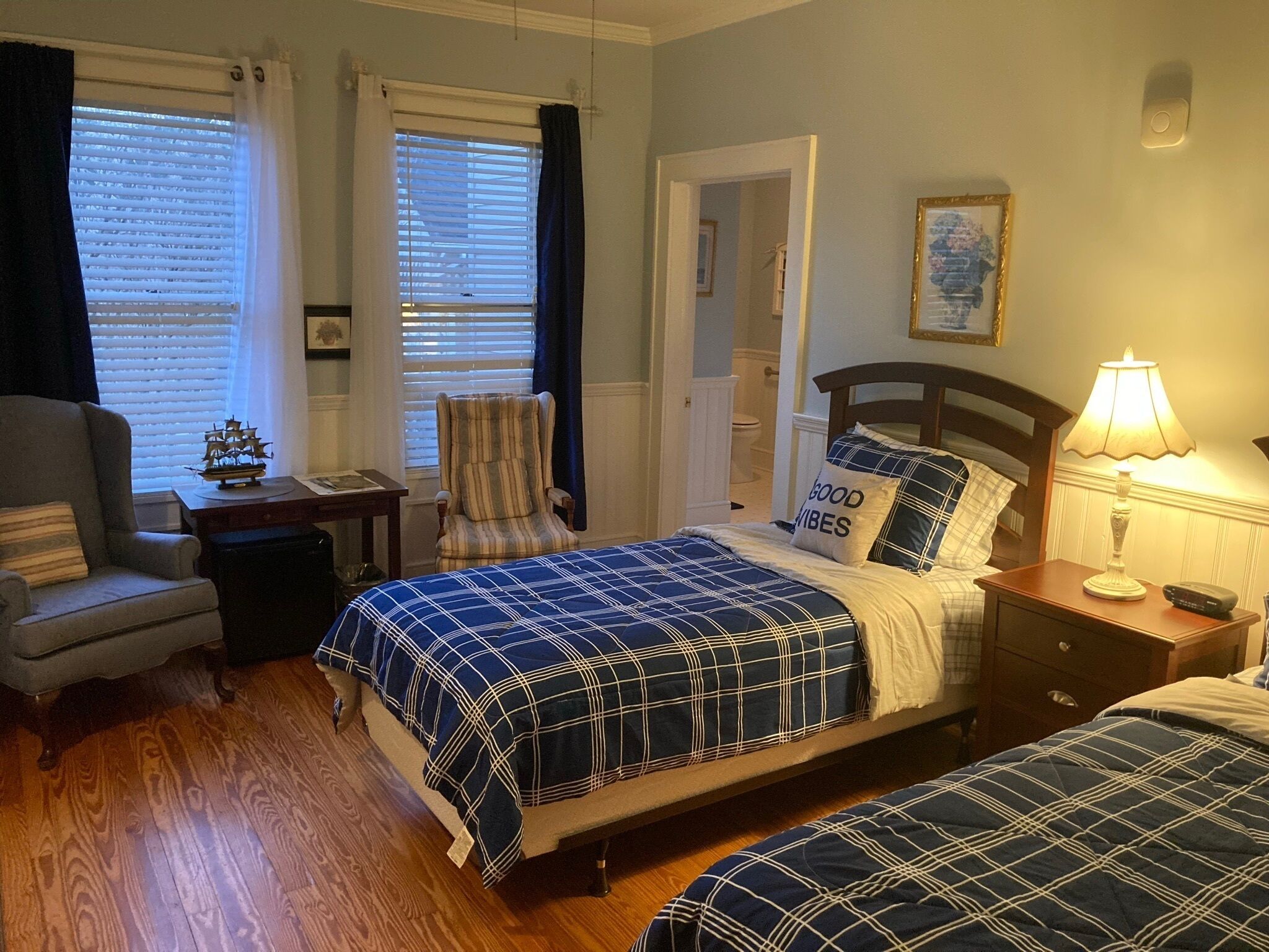 A bedroom with a bed, a chair, a nightstand, and a lamp.