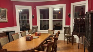 A dining room with a wooden table and chairs, a ceiling fan, and a grandfather clock. - The Historic Herren House (Waynesville)