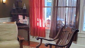 A living room with a wooden rocking chair, a sofa, a patterned rug, and a decorative fireplace. - The Historic Herren House (Waynesville)