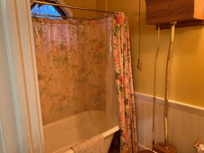 Un baño con bañera, cortina de ducha y piso de madera.