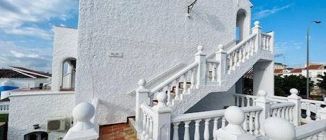 Un edificio blanco con una escalera y una farola.