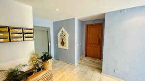 A hallway with a wooden door, a wall-mounted plant, and a tiled floor. - Apartamento La Fuente At Home by At Home Costa del (Frigiliana)