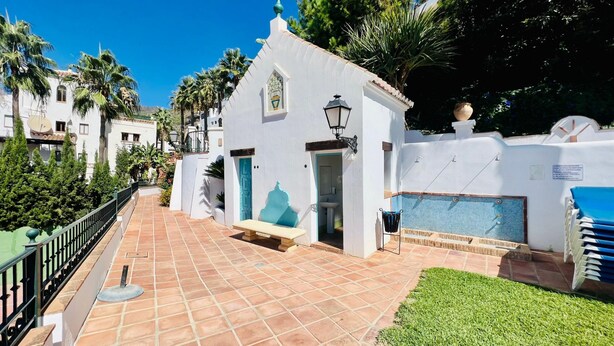 A white building with a tiled patio, a small pool, and a blue door. - Apartamento La Fuente At Home by At Home Costa del (Frigiliana)