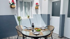 A round glass table with four wicker chairs, a bottle of wine, plates, and a bowl of grapes. - Apartamento Alboran Panama by At Home Costa del (Nerja)