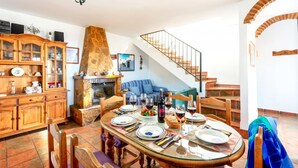 A dining area with a stone fireplace, wooden cabinets, and a staircase. - Villa Sanchez Sol by At Home Costa del Sol (Torrox)