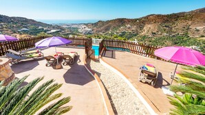 A poolside area with lounge chairs and umbrellas, a wheelchair, and a view of the surrounding landscape. - Villa Sanchez Sol by At Home Costa del Sol (Torrox)