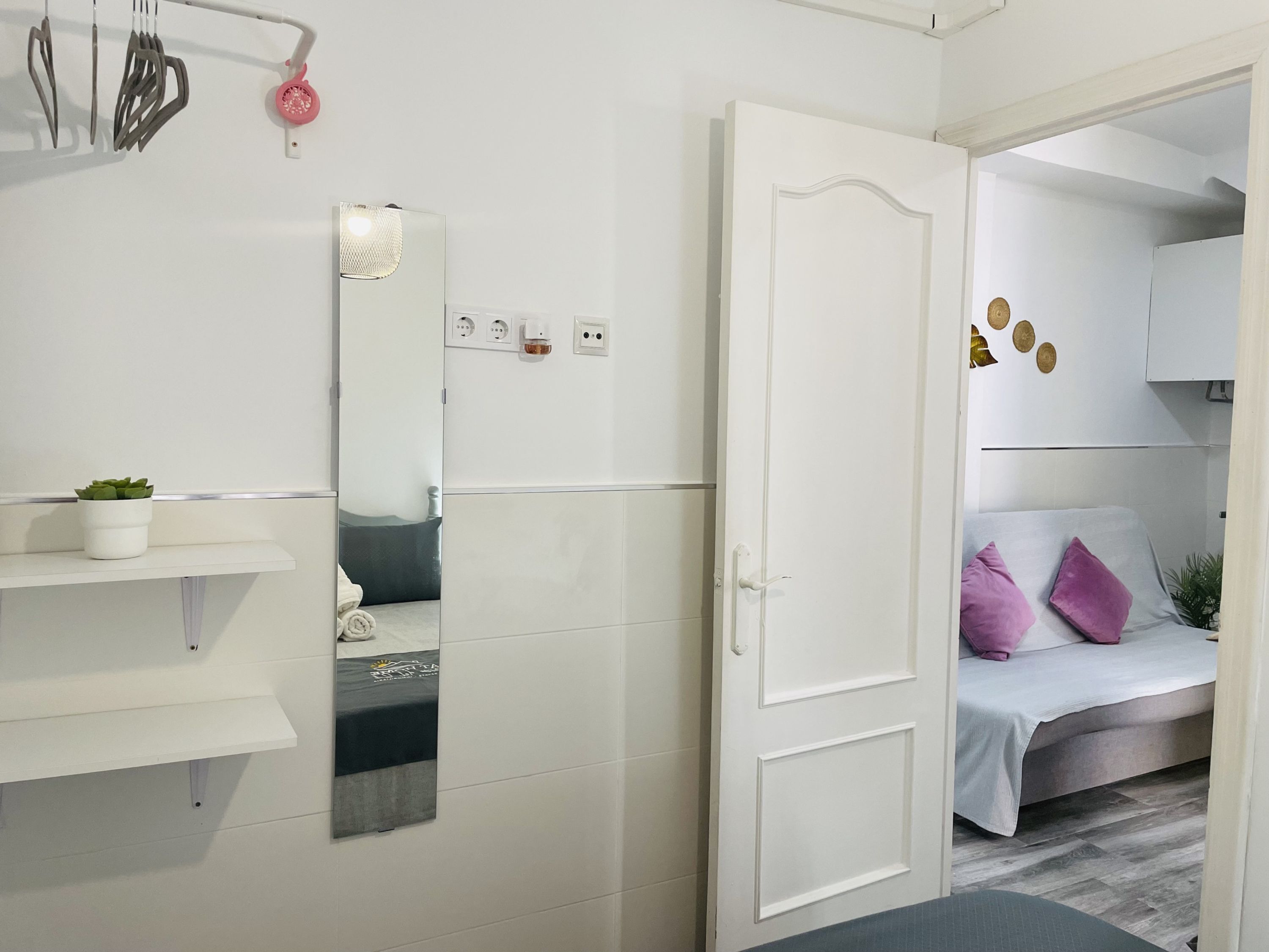 A modern bathroom with a white vanity, a mirror, and a towel rack.