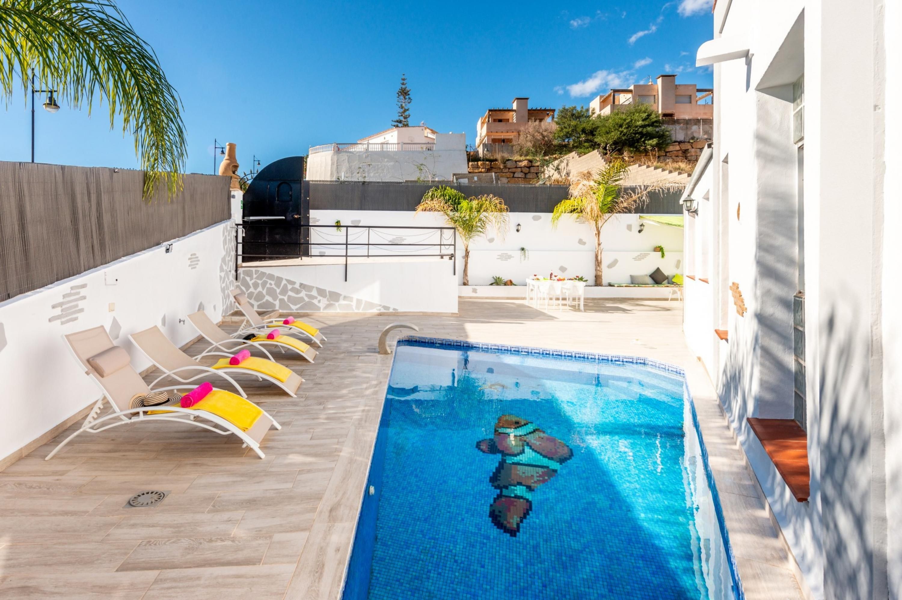 A rooftop pool area with lounge chairs and a clear view of the cityscape.
