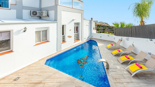 A modern pool area with a rectangular pool, lounge chairs, and a white building with large windows and air conditioning units. - Villa Marrakech in Torrox Costa (Torrox)