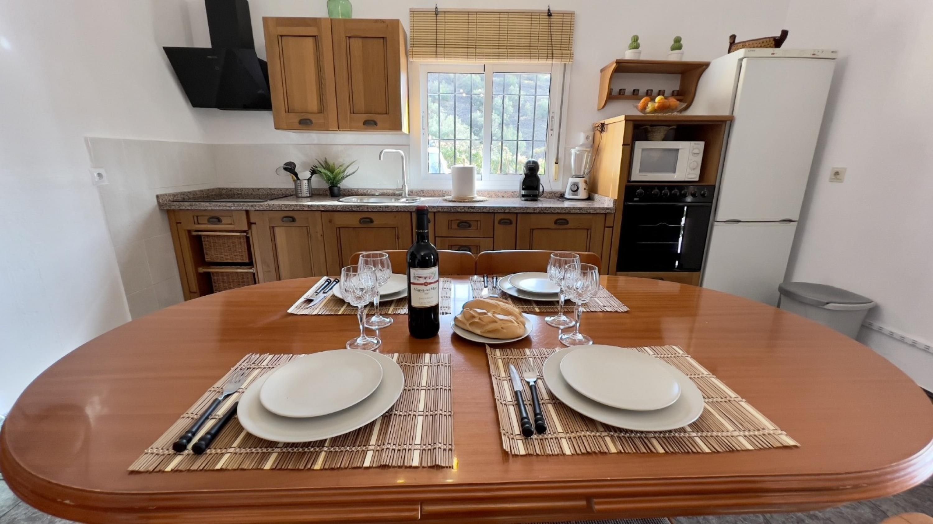 Une table à manger dressée pour quatre personnes, avec des sets de table, du vin et du pain.