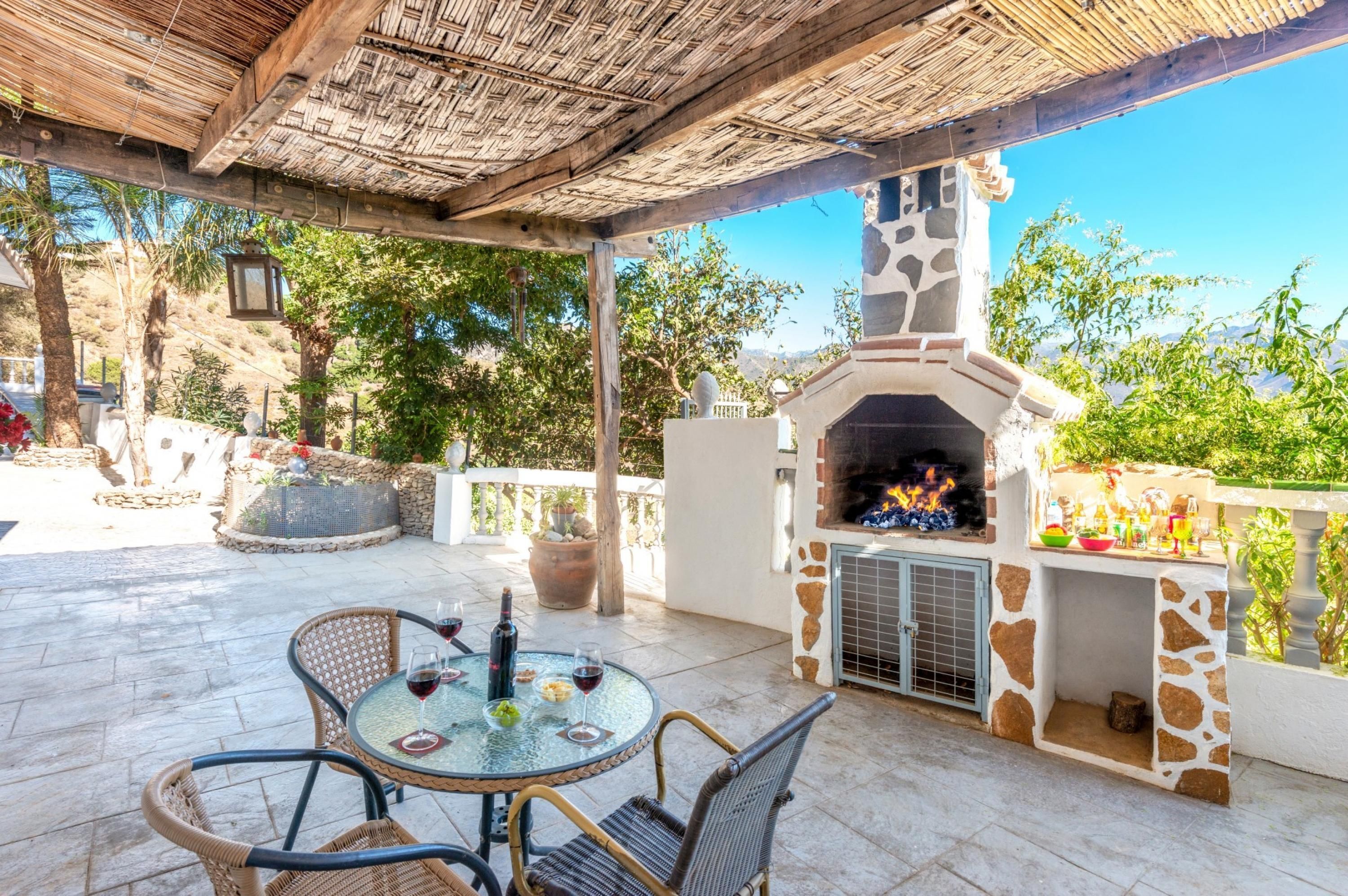 An outdoor patio with a stone fireplace, wicker furniture, and a view of the surrounding landscape.