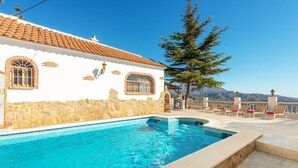 A pool area with a stone wall, a white building with arched windows, and a view of mountains. - Villa Las Palomas by At Home Costa del Sol (Torrox)
