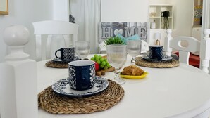 A dining table set with blue and white patterned cups, clear glasses, and a yellow plate with croissants.