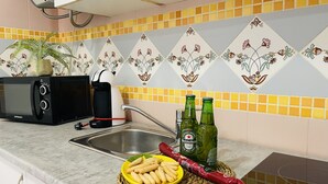 A kitchen with a microwave, toaster, and two Heineken beer bottles on the counter.